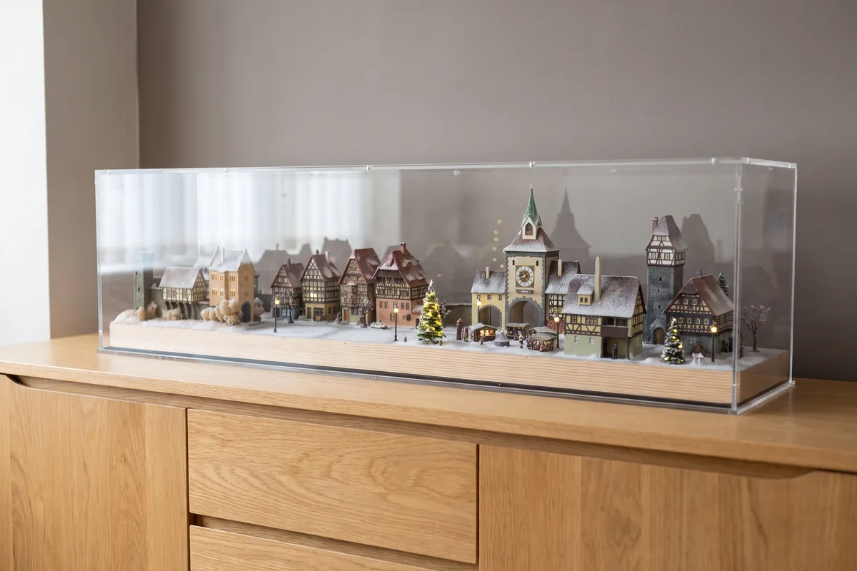 Illuminated miniature village with many half-timbered houses under a long made to measure acrylic display case