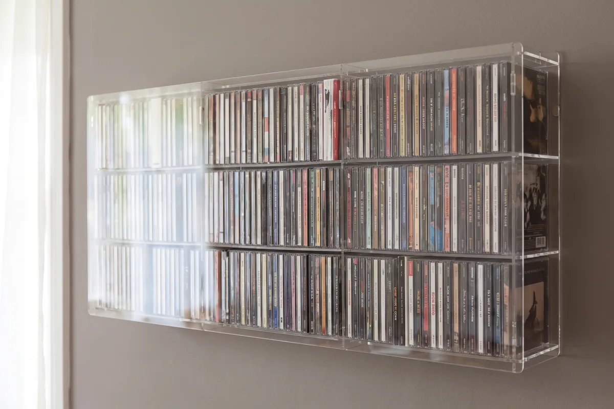 Made to measure acrylic CD/DVD rack on the wall, filled with CDs
