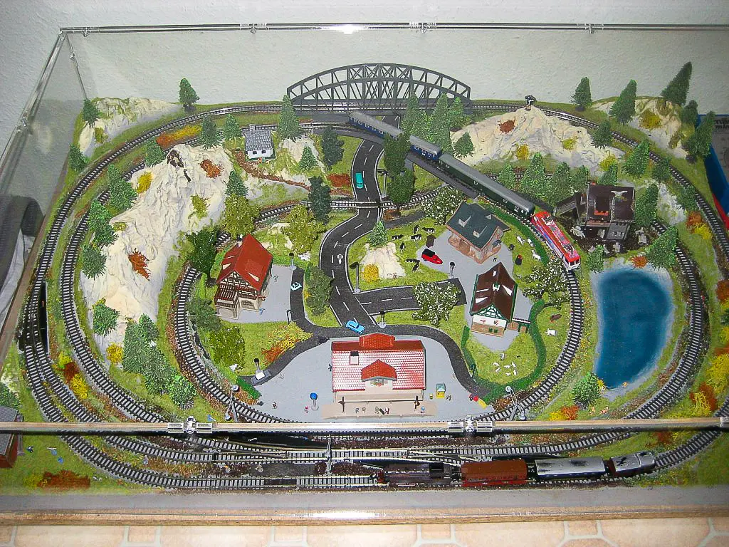 Large Sora made-to-measure display case over a complete model railway landscape with a bridge, mountains, tunnels, a lake and a station