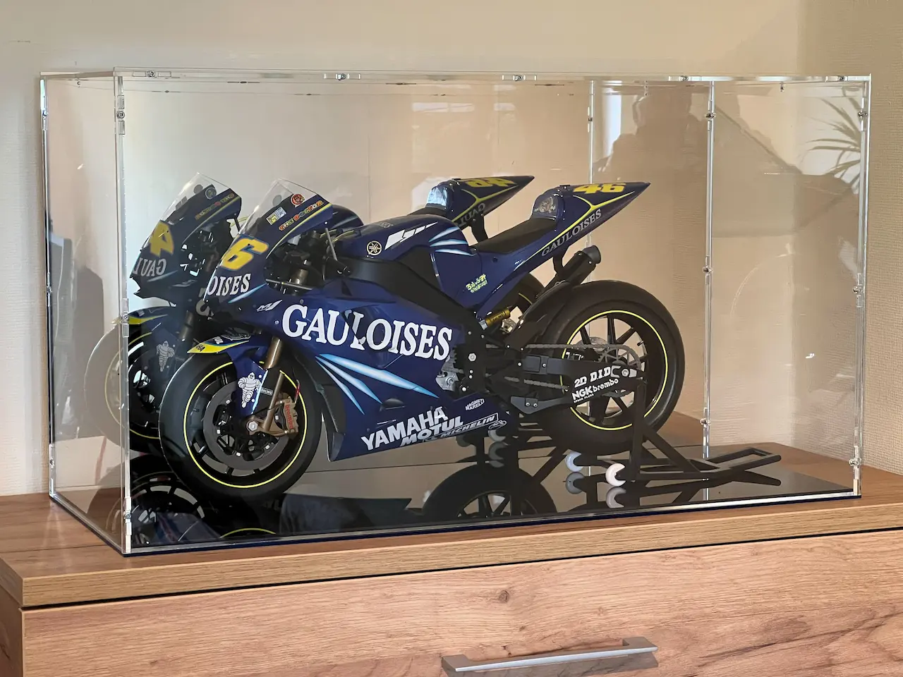Clear acrylic display case over a MotoGP model motorcycle — blue Yamaha with Gauloises sponsorship, race number 46