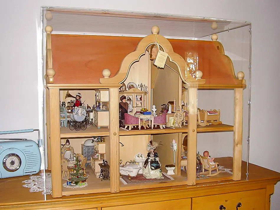 Sora made-to-measure display case over a two-storey doll’s house with miniature furniture and figures on a wooden chest of drawers